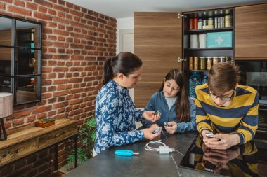 Anne kızına pilli fenerin nasıl kullanılacağını öğretirken genç kız 72 saatlik acil durum telsizini kontrol ediyor. Aile hazırlığı alarmı, öngörü ve kendi kendine yetme stratejisi.