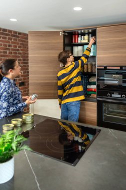 Evde 72 saatlik hayatta kalma kiti hazırlayan aile, kendi kendine yetebilme eğitiminin bir parçası. Anne oğluna teneke kutu yiyecek ve bozulmaz mallarla dolu bir acil durum yiyecek kilerinin nasıl stoklandığını öğretiyor..