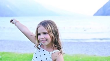 A little girl is dancing in the open space. Child near Lake Garda in Italy. Happy moment. High quality FullHD footage