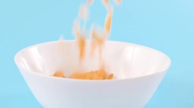 Cornflakes. Dry breakfasts are poured into a bowl. Vitamin food for children and adults. Slow motion food. Bright colours. 4k footage