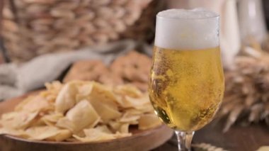 Glass of light craft beer on a wooden table. Beer is poured into a glass with foam and bubbles. for social media or advertising. beer texture. High quality 4k footage. 