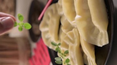 Dim sum. Ev yapımı Çin köfteleri siyah bir tabakta servis edilir. Yemek çubuklarıyla yiyorlar. Doğu mutfağı, geleneksel öğle yemeği için hafif atıştırmalıklar. dikey video