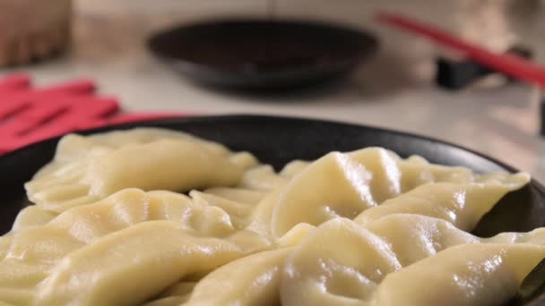 ディム 自家製中華餃子はブラックプレートで提供されています 箸で食べる 東洋料理 伝統的なランチの軽食 垂直ビデオ — ストック動画