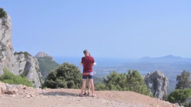 Loving couple in the mountains. Man and woman on a hiking trip in summer. Horizon, mountains, sea and blue sky. High quality FullHD footage