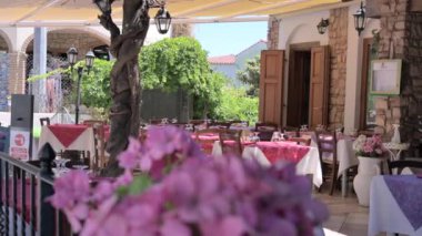 Italian restaurant or trattoria in classic style with red and white tablecloths. Summer restaurant with flowers on the street. High quality 4k footage
