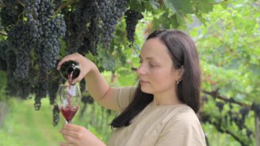 Beautiful woman dreaming tasting red wine enjoying summer stay in vineyards on lovely sunny day. woman drinking red wine at vineyard. harvest season. High quality photo