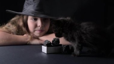Little girl in a witchs hat or bifanya with black kittens. Black cat and coal for a naughty child on January 6th. Traditional catholic holiday in italy for children after christmas. Epifanya. 4k