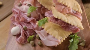 Hilal çiçeği. Emilia Romagna bölgesinin yiyeceği, kızarmış ekmek gnocco fritto ya da Crescentina. İtalya 'da aperatif veya aperatif. Prosciutto crudo, mortadella, Milano salamı, kapari, peynir ile Creshantina 