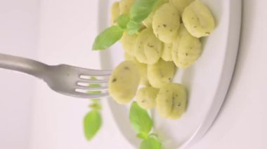 İtalyan gnocchi. Geleneksel İtalyan yemekleri. Parmesanlı ve fesleğenli el yapımı patates topları. Vejetaryenler için yemek ve tipik İtalyan mutfağı aşıkları. Ev yapımı makarna. Yüksek kalite 4k görüntü