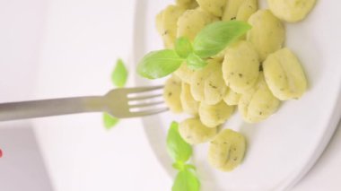 İtalyan gnocchi. Geleneksel İtalyan yemekleri. Parmesanlı ve fesleğenli el yapımı patates topları. Vejetaryenler için yemek ve tipik İtalyan mutfağı aşıkları. Ev yapımı makarna. Yüksek kalite 4k görüntü