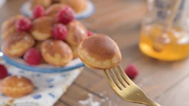  Altın Hollandalı Poffertjes 'in yakın çekimi odak noktasında. Lezzetli geleneksel mini krepler tabakta. Mavi desenli beyaz bir tabakta mini krep.