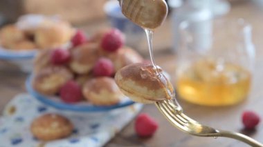  Altın Hollandalı Poffertjes 'in yakın çekimi odak noktasında. Lezzetli geleneksel mini krepler tabakta. Mavi desenli beyaz bir tabakta mini krep.