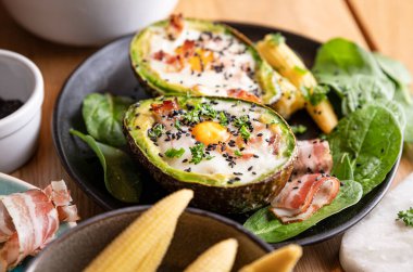 Yumurta ve pastırmayla Avokado pişiriyorum. Kız sağlıklı bir yemek hazırlıyor, ellerini ve ürünlerini çerçeveye yakın plan yapıyor. Tam beslenme için kahvaltı.