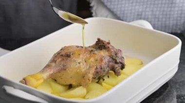 Patatesli kızarmış ördek bacağı ve fırınlanmış fırın tabağı. Yemek blogları, özel dersler ve medya içeriği için fırında kızartılan ördek bacağı, patates ve aromalı otların elit bir videosu.