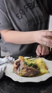 Patatesli kızarmış ördek bacağı ve fırınlanmış fırın tabağı. Yemek blogları, özel dersler ve medya içeriği için fırında kızartılan ördek bacağı, patates ve aromalı otların elit bir videosu.