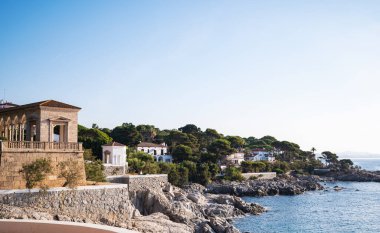 Rocky Shoreline ve Villas Akdeniz manzaralı İspanyol Sahil Manzarası. Kayalık kıyılar, geleneksel Akdeniz villaları ve açık mavi gökyüzüne karşı yemyeşil yemyeşil. 