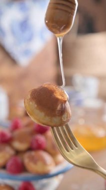 Hollanda Mini Gözlemeleri. Poffertjes üzerine şurup serpiştirilmiş tatlı kahvaltı. Poffertjes olarak bilinir, şurup serpiştirilmiş ve lezzetli bir kahvaltı ya da tatlı olarak sunulmuştur. Yemek blogları ve sosyal medya için mükemmel.