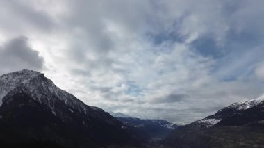 Karla kaplı tepeleri dramatik bulutlu bir gökyüzünün altında görkemli dağ manzarası. Doğanın nefes kesici bir görüntüsü güzellik, seyahat, macera ve manzara için mükemmel. Yüksek kaliteli FullHD görüntüler