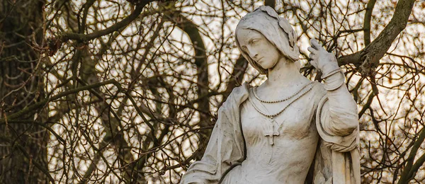 Religious woman sculpture and leave less tree background, paris, france