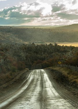 Arka planda küçük tepe ve gökyüzü olan boş toprak yol, Tierra del Fuego vilayeti, Arjantin