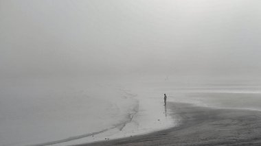 Ramirez plajında sisli bir kış günü sahilde tek başına duran kişi. Parque rodo negihorhood, Montevideo City, uruguay.