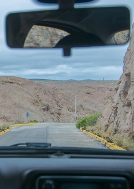 Companion driver point of view at patagonia highway surrounded by rocky mountains, chubut province, argentina clipart