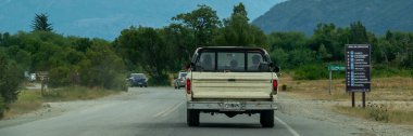 Lago Puelo, Argentina; January 7 2023: Outdoors highway and snowy andes range mountains at background, lago puelo national park, chubut province, patagonia, argentina clipart