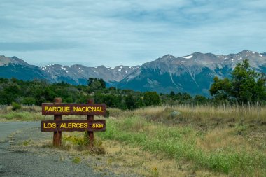 Los alerces national park wooden signpost at route and andes range mountains at background, chubut province, patagonia, argentina, clipart