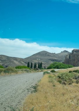 Piedra Parada 'da kayalık dağları aşan toprak yol. Patagonya, Chubut, Arjantin' de bulunan antik bir volkanik çevre. 
