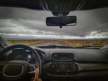 Inside car shot depicting a person driving higway at steepe patagonia landscape, chubut province, argentina clipart