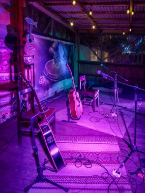 Piriapolis, Uruguay: 25 Şubat 2024: Canlı müzik performansı için küçük, samimi bir sahne. Kurulumda birden fazla akustik gitar, mikrofon standı ve kablolar yer alıyor..