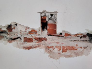 Duvarın açıkta kalan kısmı su tesisatında, kısmen yıkılmış duvarın içine yeşil borular döşenmiş, tuğlalar ve askerler ortaya çıkıyor.