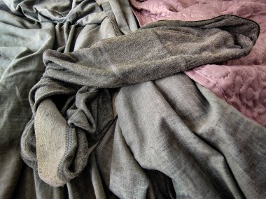 Yüksek açılı yakın çekim. Gri boxer şortlar. Yatağın üzerinde aynı renkte çarşaflar var.