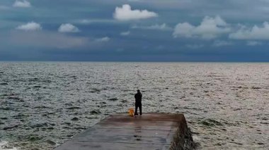 Rio de la Plata nehrinin önünde balık tutan yetişkin bir adam, Montevideo şehrinin varoş bölgesi, uruguay