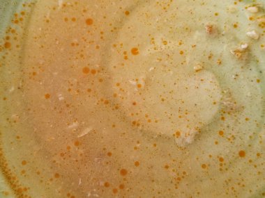 Yüzen yağ baloncuklarıyla ev yapımı sıcak çorba yüzeyi aşırı yakın çekim. Renk, doku ve sıcaklığa odaklanmış minimalist kompozisyon. Rahatlatıcı ve besleyici bir yemek önerir..