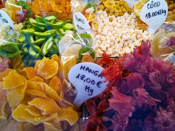 Açık plastik poşetlerde kurumuş meyvelerin yer aldığı renkli bir piyasa görüntüsünün orta açıdan çekilmiş hali. Ağırlık ve tipe göre etiketlenen bileşim, canlı ve organik bir düzende bolluk ve çeşitliliği yakalar.