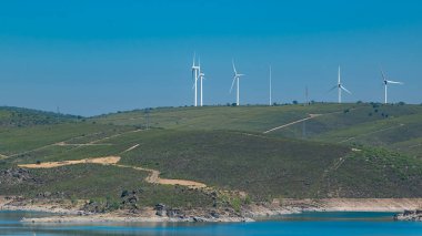 Yuvarlanan tepelerin arasında kurumuş arazi ve en az bitki örtüsü olan sakin mavi gölün göz hizasında görüntüsü..