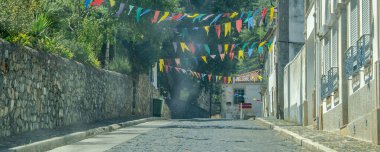 Binalarla dolu ve asılmış renkli bayraklarla, bragancalarla, Portekizlilerle dolu bir kaldırım taşı caddesinin göz hizasında manzarası