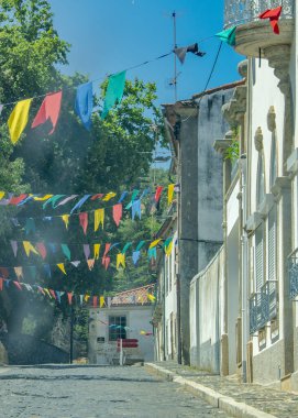Binalarla dolu ve asılmış renkli bayraklarla, bragancalarla, Portekizlilerle dolu bir kaldırım taşı caddesinin göz hizasında manzarası