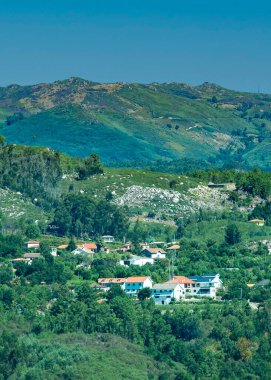 Resimli bir dağ köyünün yüksek açılı görüntüsü orman yamaçlarında, fafe 'de, braga bölgesinde, Portekiz' de kümelenmiş evler.