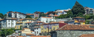 Porto yamacının geniş açılı görüntüsü terracotta çatısı olan geleneksel evlerle dolu, gün ışığı altında katmanlar halinde dizilmiş..