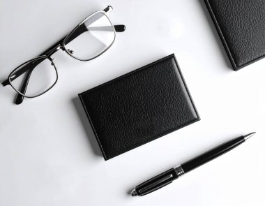 Tek bir modern siyah kartvizitin yüksek açılı görüntüsü beyaz bir masanın üzerinde.