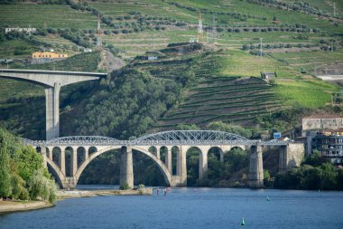 Douro nehri boyunca uzanan yüksek açılı iki köprüden yüksek açılı görüntü tepenin altındaki üzüm bağları terasları, açık gökyüzü altında peso da regua, Portekiz 