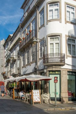 Braga, Portugal: August 14 2023: Daylight view of an outdoor cafe with tables and chairs on a traditional street in Braga city, portugal