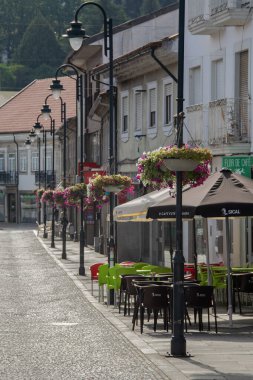Vila Pouca do Aguiar, Portugal: August 14 2023: iA view down a narrow cobblestone street in Vila Pouca de Aguiar, Portugal, with outdoor cafe tables ready for customers. 