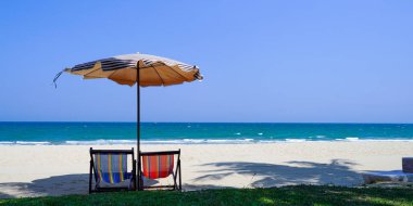 Boş plaj sandalyesi ve deniz altyapısı olan şemsiye.