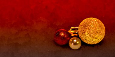 Kırmızı takılar ve siyah arka planda altın ışıklarla Noel süslemeleri.