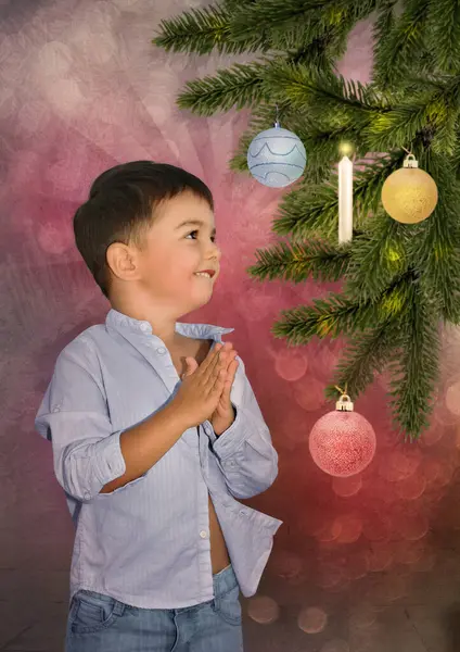 小男孩脸上挂着笑容 看着圣诞树上摆放着玩具 免版税图库图片