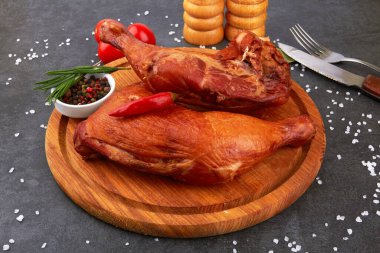 Siyah taş bir yüzeyde tütsülenmiş tavuk butları.