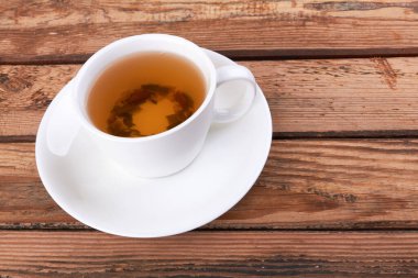 Ahşap arka planda bir fincan yeşil çay.